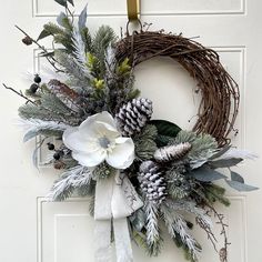 a wreath with white flowers and greenery hangs on the front door to give it a festive touch