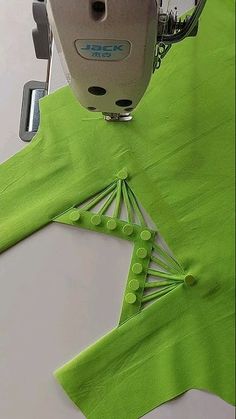 the sewing machine is working on the green material that has been sewn into it