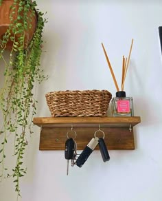 a wooden shelf with keys and plants on it next to a wall mounted key holder