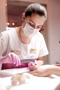 a woman in a white shirt and pink gloves is cutting something with a large knife