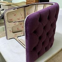 an open purple suitcase sitting on top of a white table next to a bed and dresser