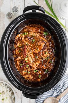 an overhead view of a slow cooker filled with chicken and rice, garnished with green onions