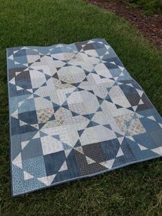 a blue and white quilt laying on the grass