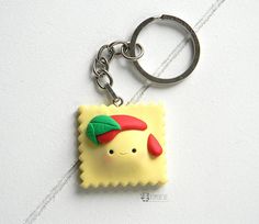 a rubber keychain with a cartoon character wearing a red hat and green leaf on it