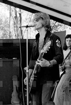 a man standing next to a woman holding a guitar on top of a stage in front of a microphone