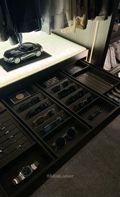 an open drawer with several pairs of watches and other items on it in front of a mirror