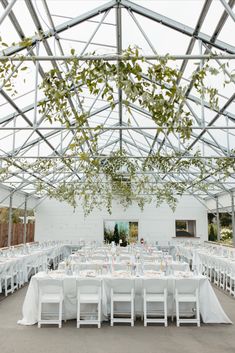 an indoor venue with tables and chairs set up for a wedding reception under a glass roof