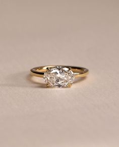 an engagement ring with a single diamond in the center on a plain surface, close up