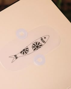 a white box with a black and white design on the lid that has a fish in it