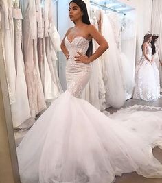 a woman standing in front of a mirror wearing a wedding dress