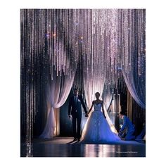 the bride and groom are walking down the aisle with beaded curtains hanging from the ceiling