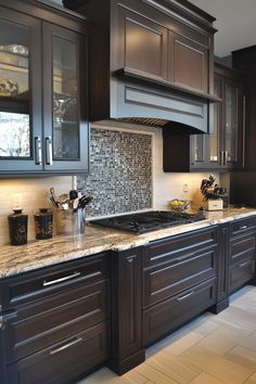 a kitchen with black cabinets and marble counter tops