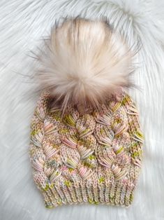 a knitted hat with a pom - pom sitting on top of white fur