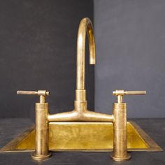 a brass faucet with two handles and nozzles sits on a black surface