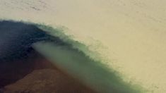 a man riding skis down the side of a snow covered slope next to a large wave