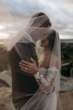 a bride and groom embracing each other under a veil