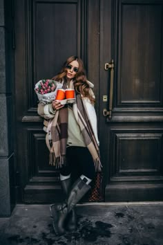 a woman standing in front of a door holding a cup