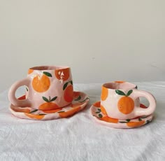 two cups and saucers with oranges painted on them