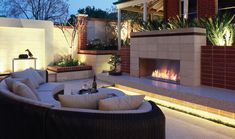 an outdoor living area with couches and fire place in the center at night time