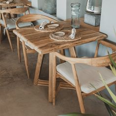 a wooden table with chairs and plates on it