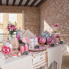 a table topped with lots of candy and candies next to a brick wall in a room