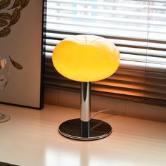 a yellow lamp sitting on top of a table next to a window