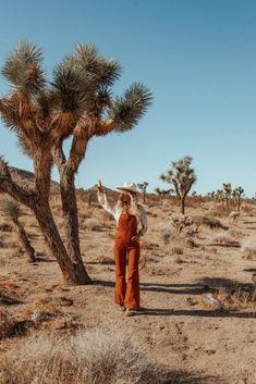 a woman standing next to a tree in the desert