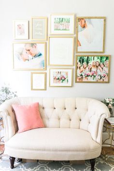 a white couch sitting in front of pictures on the wall