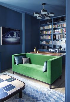 a green couch sitting in front of a book shelf filled with books