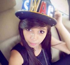 a young woman wearing a hat with the word swag on it's brim