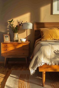 a bed sitting next to a wooden dresser with a lamp on it's side