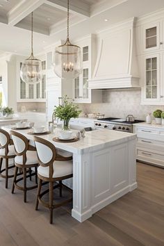 a kitchen filled with lots of white furniture and counter top space next to an island