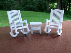 two white plastic rocking chairs sitting on top of a table