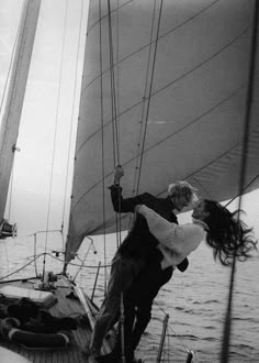 a man and woman hug on the deck of a sailboat