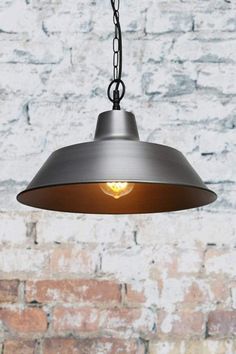 a light hanging from a chain in front of a brick wall