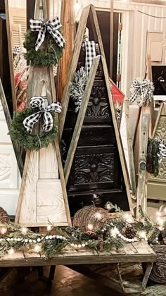 three wooden christmas trees with lights on them in front of a door and other decorations