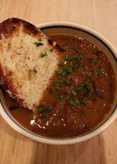 a bowl filled with soup and bread on top of a wooden table