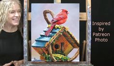 a woman standing next to a painting of a red bird on top of a birdhouse