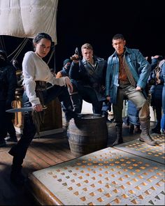 a group of people standing on top of a wooden deck next to a pirate ship