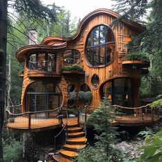 a wooden house in the woods with stairs leading up to it's second story