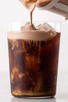 someone is pouring coffee into a glass with ice