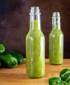 two bottles filled with green stuff next to peppers