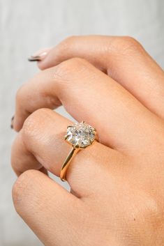 a woman's hand holding a ring with a diamond on it and the middle finger