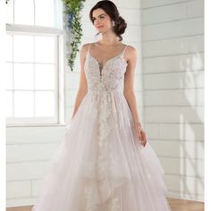 a woman in a wedding dress standing on a wooden floor with white walls and windows