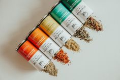 six different types of spices are lined up on a white surface, with one in the foreground