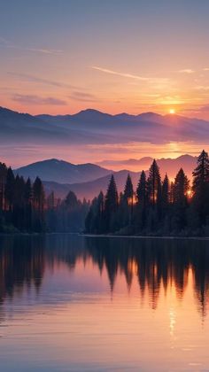 the sun is setting over a lake with mountains in the background and trees on both sides