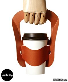 a coffee cup holder made out of wood and leather with an arm holding a coffee cup