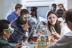 two students and an instructor working in a science lab with flasks on the table