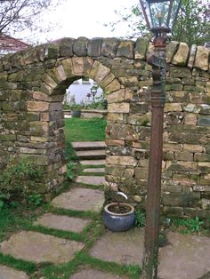 an old fashioned lamp post in the middle of a stone wall with steps leading up to it