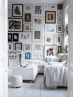 a living room filled with white furniture and pictures on the wall